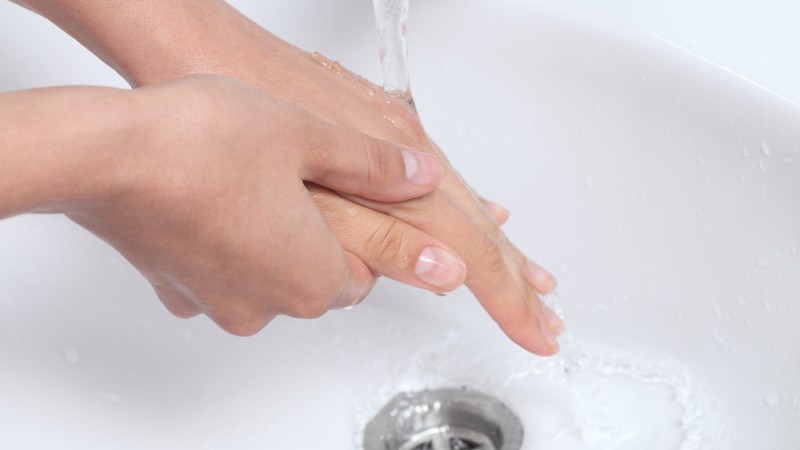 En person tvättar händerna i ett handfat